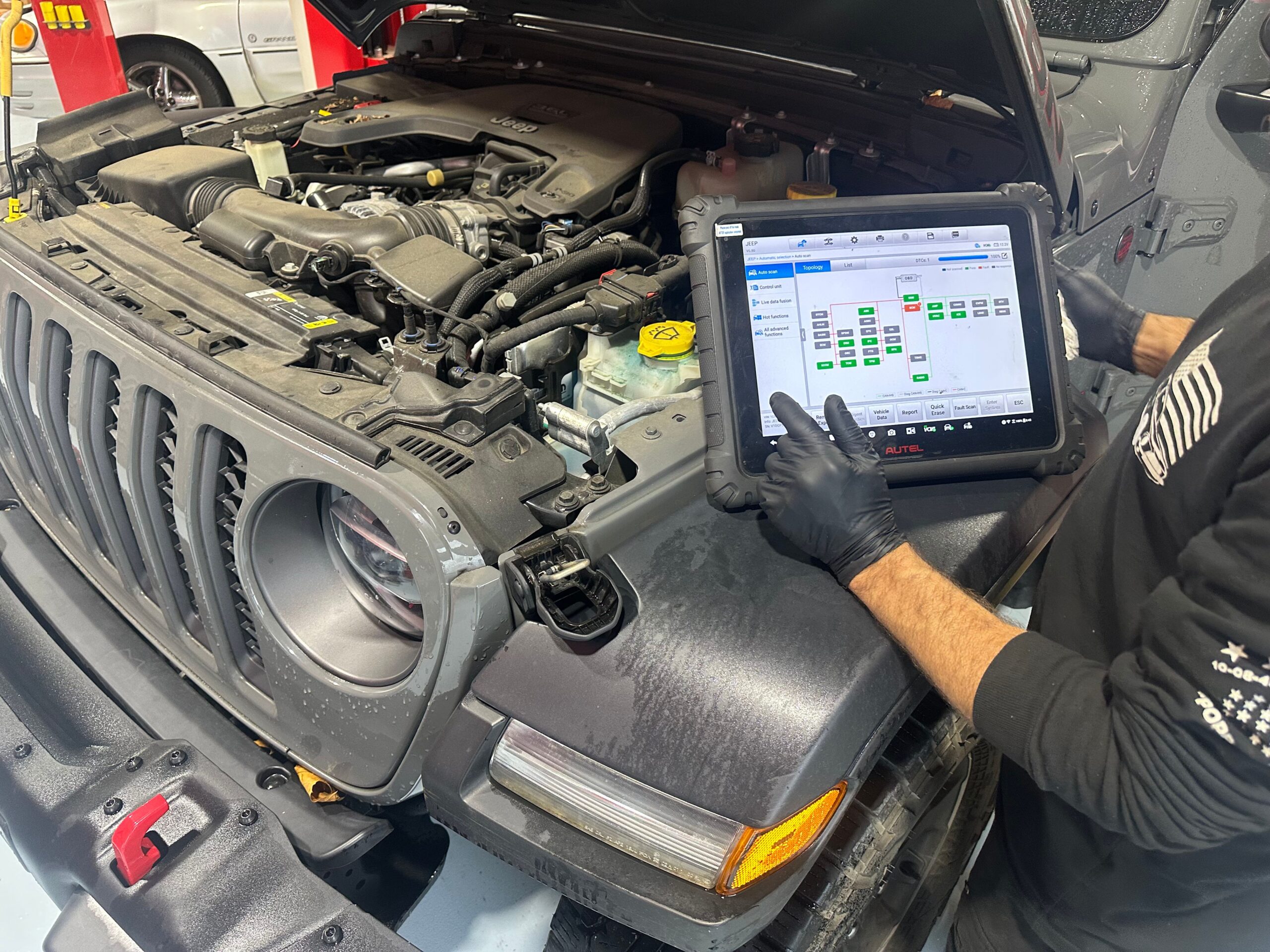 mechanic evaluating diagnostics on tablet with vehicle hood open