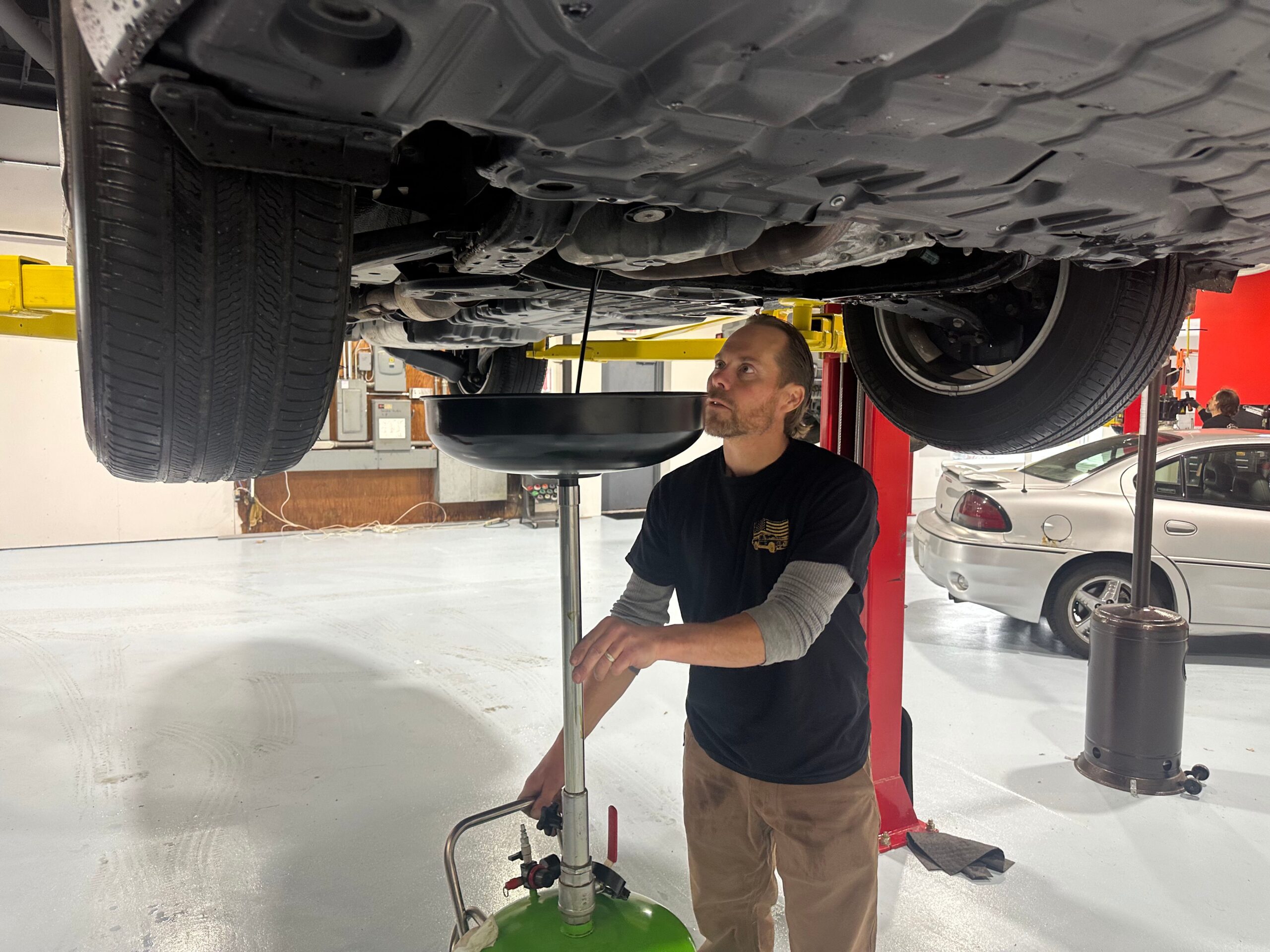 mechanic Jason Glemser conducting oil change observing oil drain